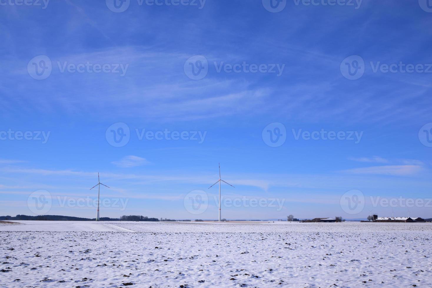 Winter flat landscape with snow up to the horizon in Swabia. Wind turbines can be seen in the background photo