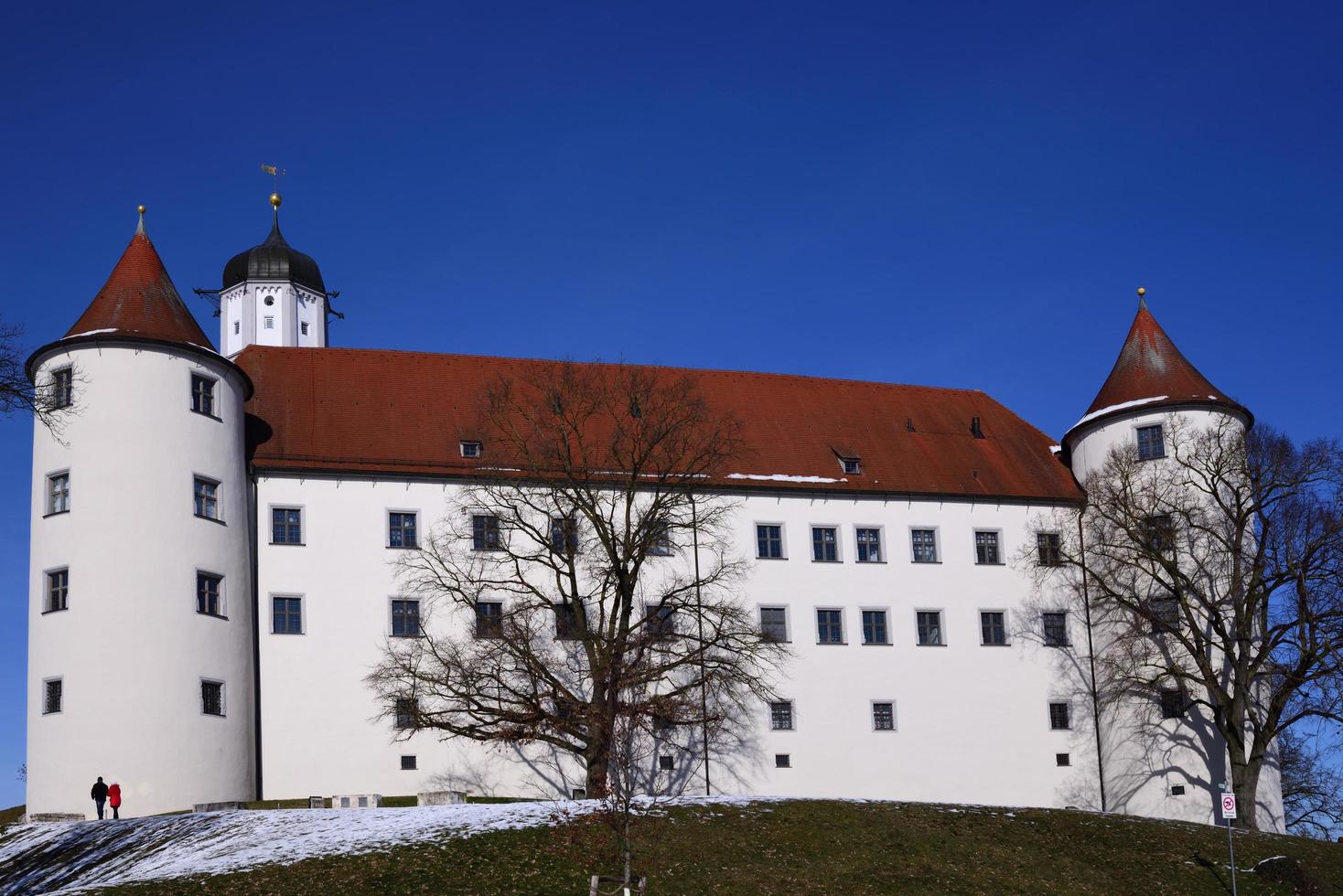 The historic castle in Hoechstaett stands on a hill in front of a blue sky, behind bare trees, in the sunshine photo