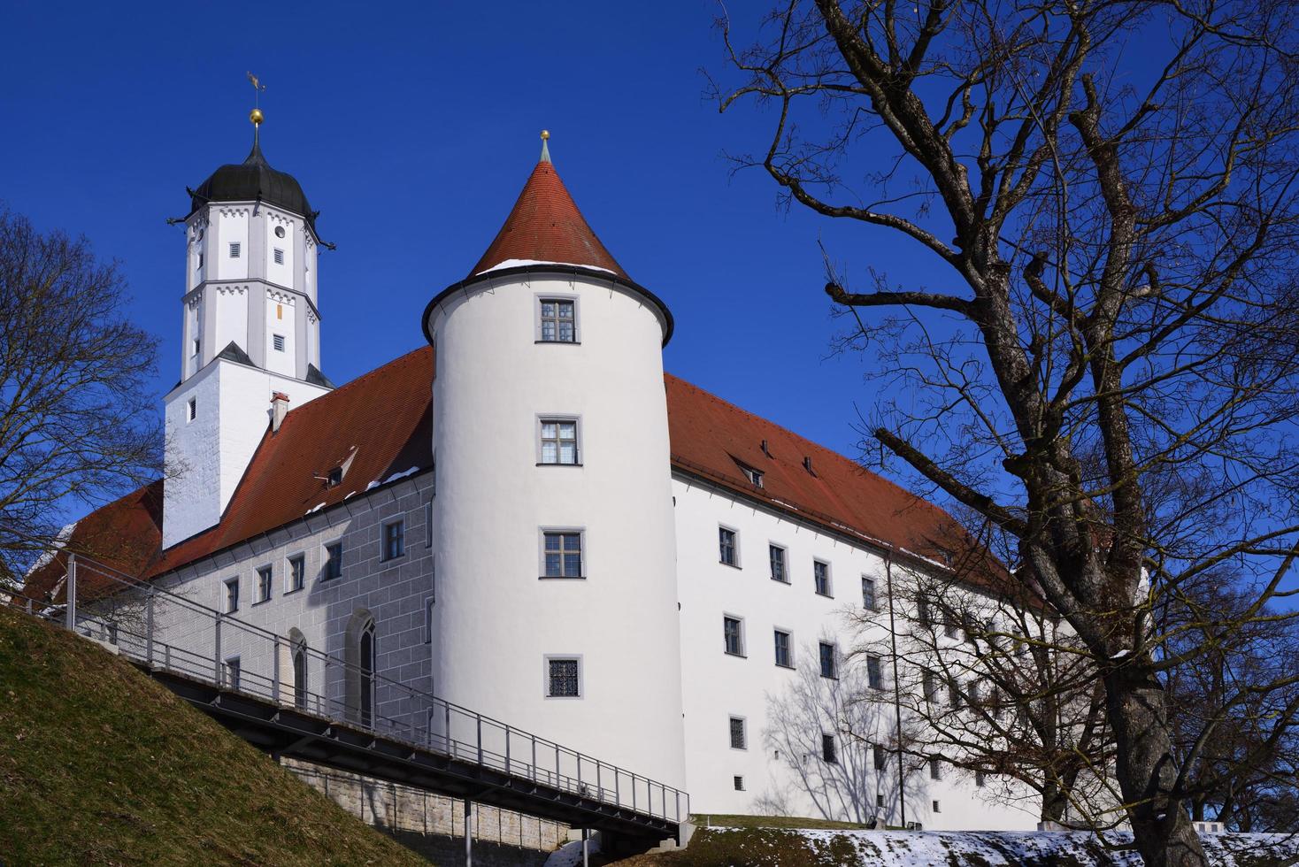 The historic castle in Hoechstaett stands on a hill in front of a blue sky, behind bare trees, in the sunshine photo