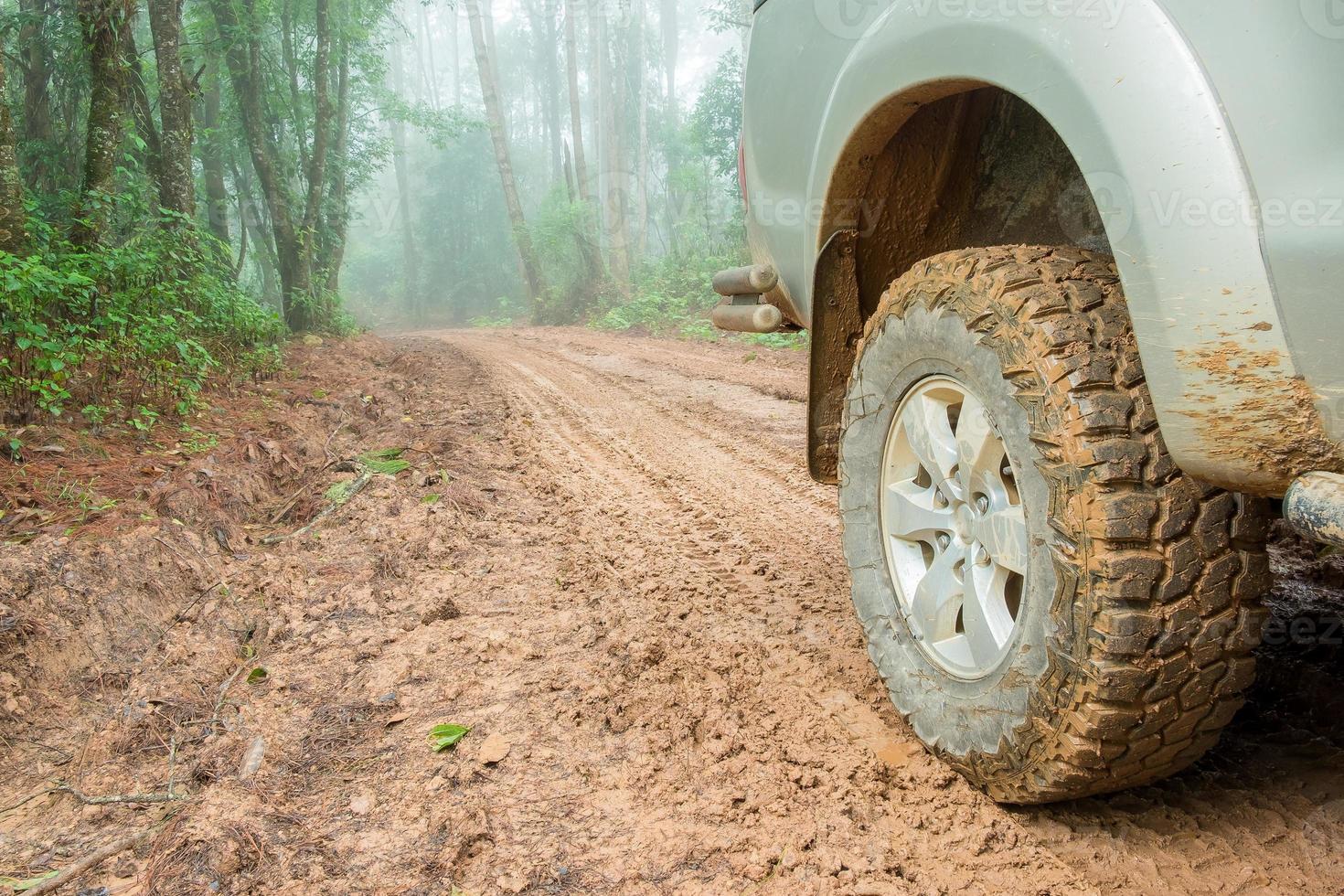 Wheel truck closeup in countryside landscape with muddy road. Extreme adventure driving 4x4 vehicles for transport or travel or off-road races in outdoor nature. 4wd tire automobile on dirt mountain. photo