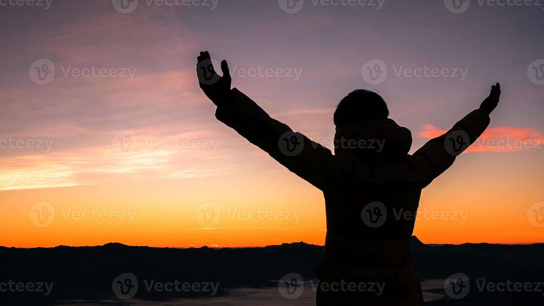 Silhouette of human person hands open palm up worship in sky sunset or sunset. Catholic adult man pray and hope on mountain. Christian religion concept background. fighting and victory for god photo