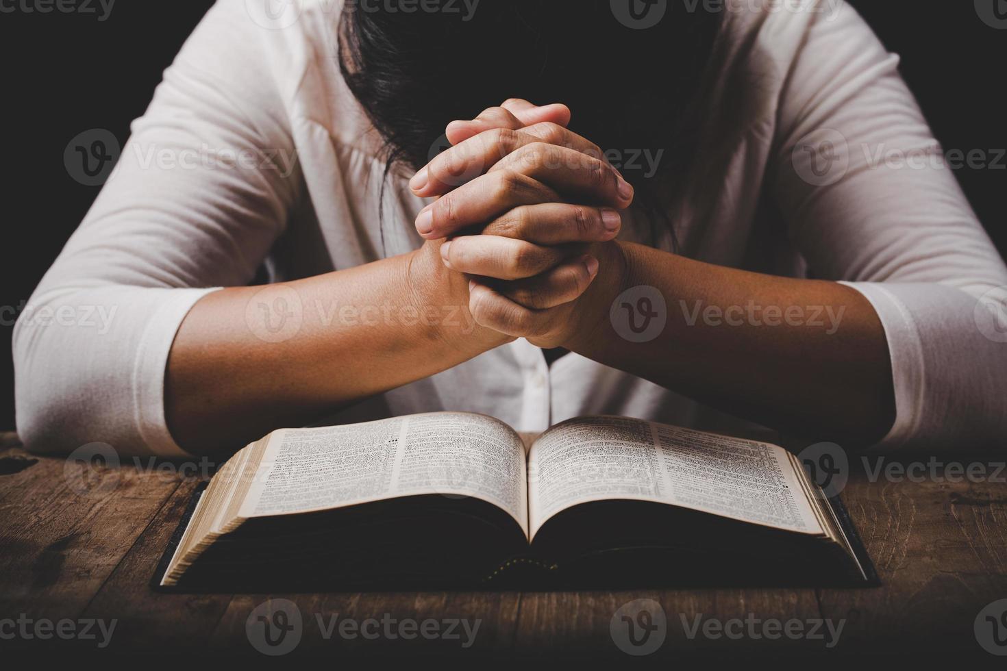 christian woman hand on holy bible are pray and worship for thank god in church with black background, concept for faith, spirituality and religion photo