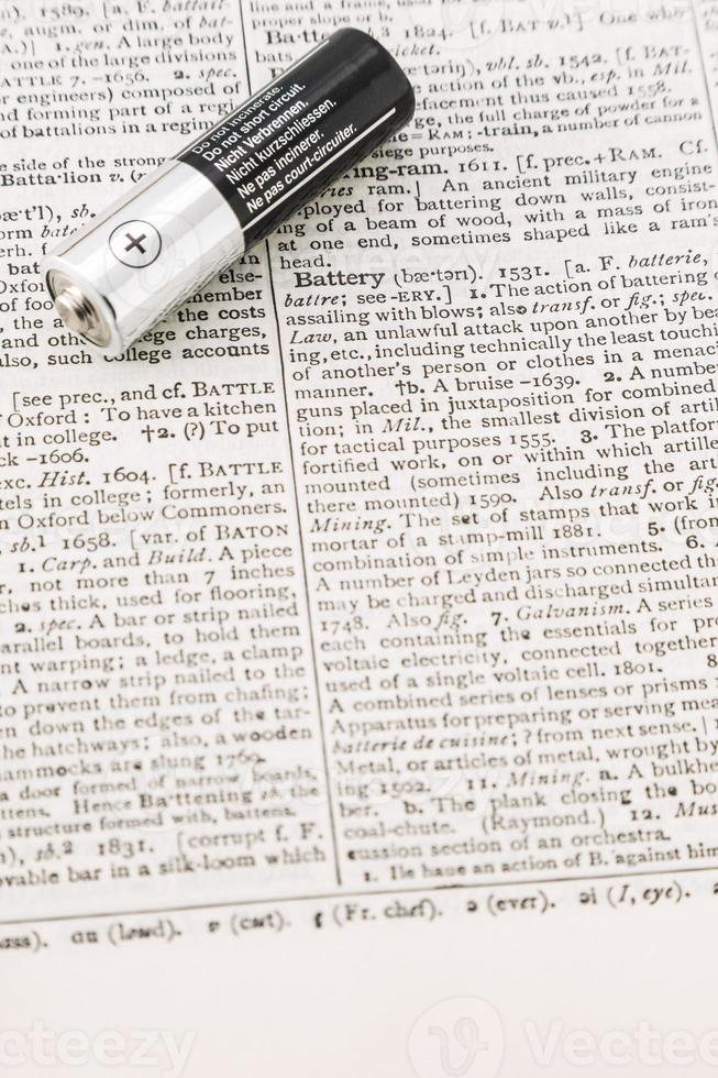 Vertical closeup of the silver and black battery on a dictionary page. photo