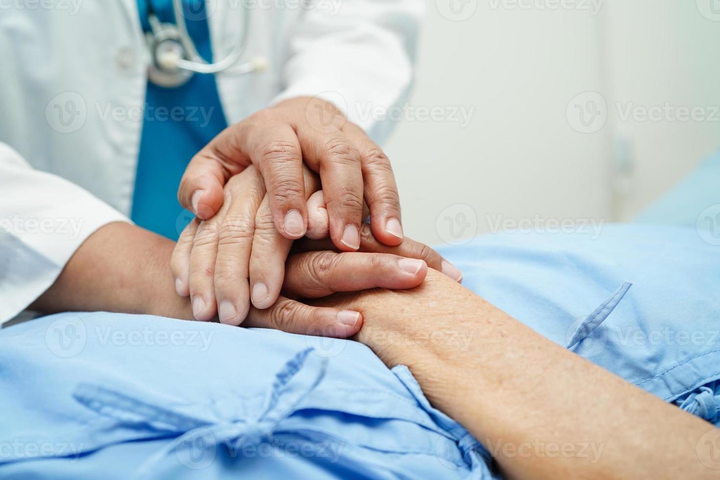 médico tomados de la mano paciente anciana asiática, ayuda y atención en el hospital. foto