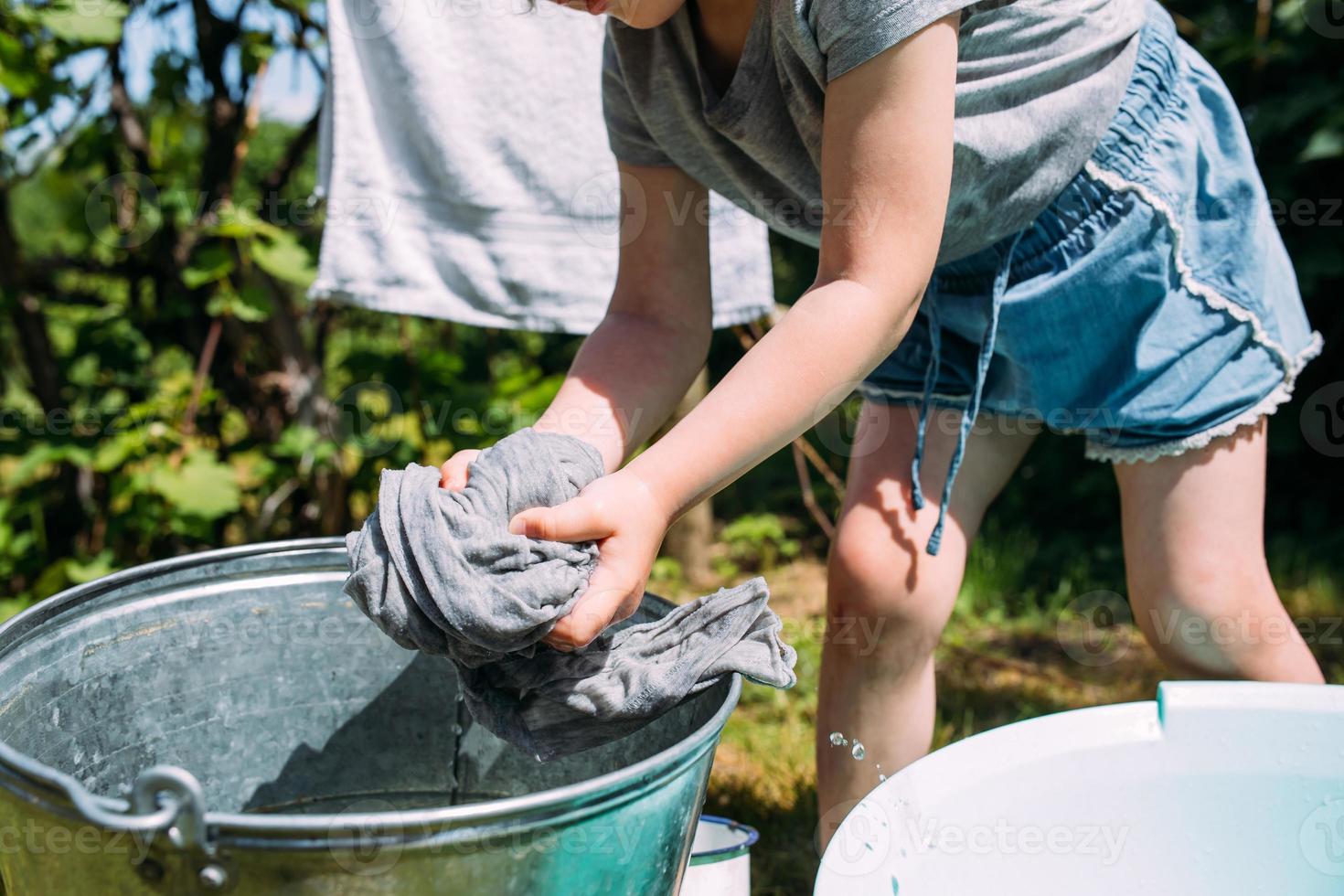 Little preschool girl helps with laundry. Child washes clothes in garden photo