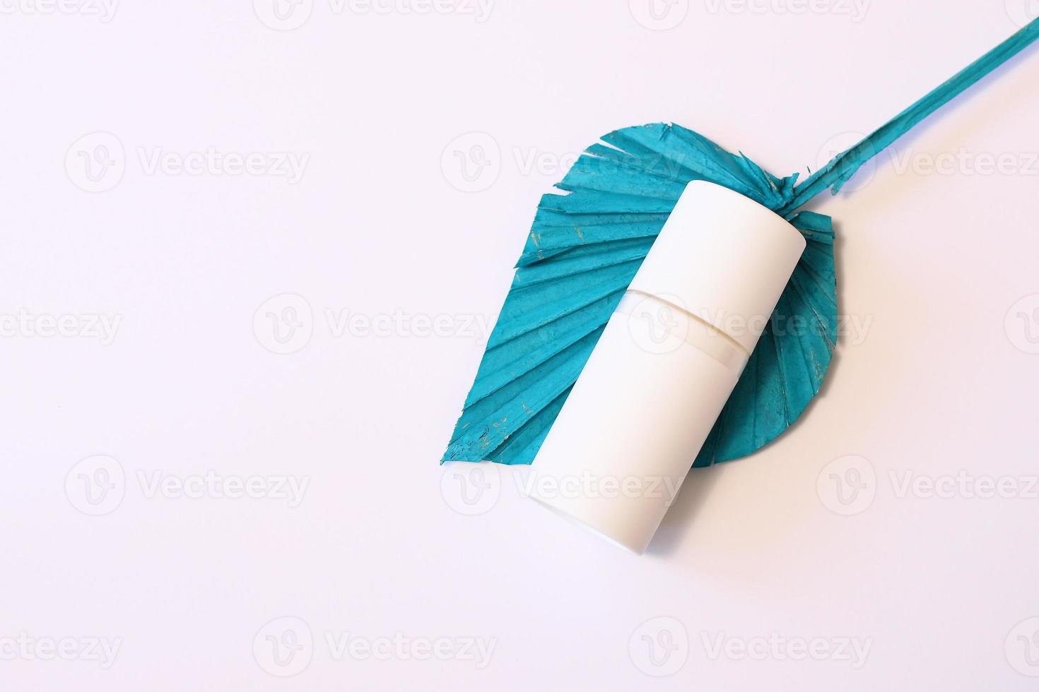 White cosmetic bottle mockup on blue dried flower photo