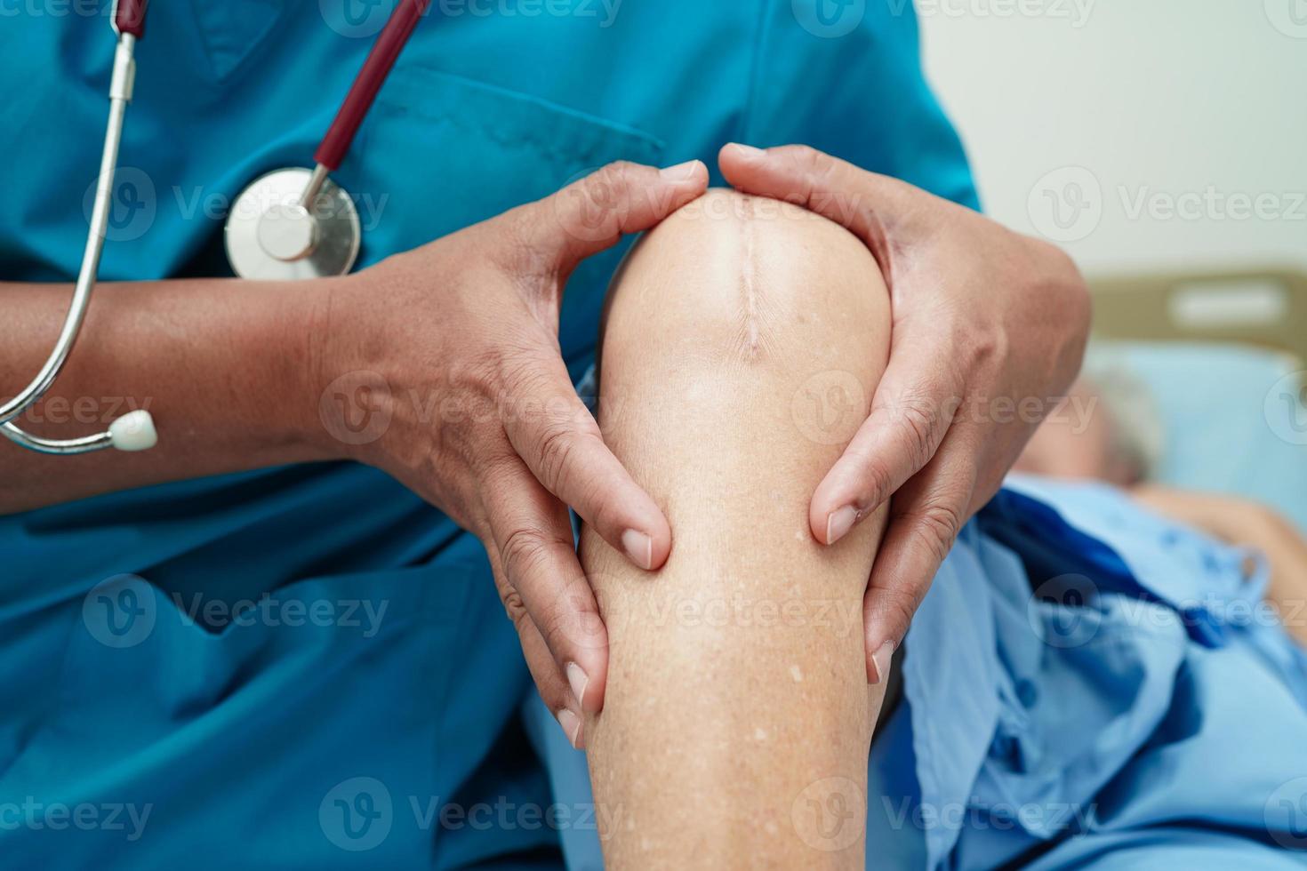 Doctor checking Asian elderly woman patient with scar knee replacement surgery in hospital. photo