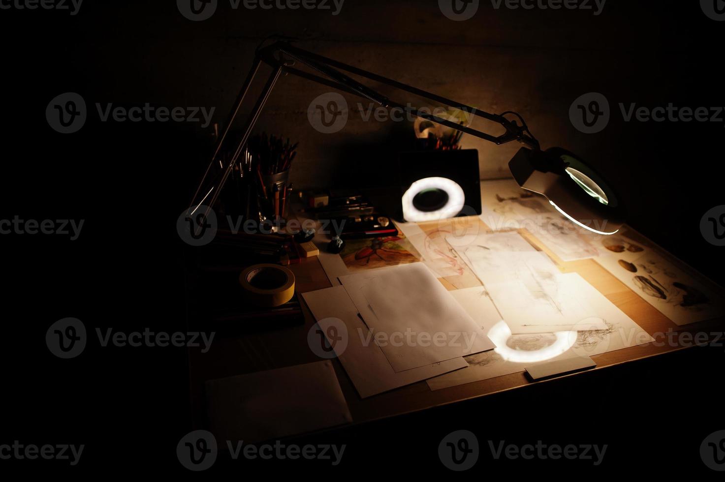 Desk with turn on lamp and painting items. photo