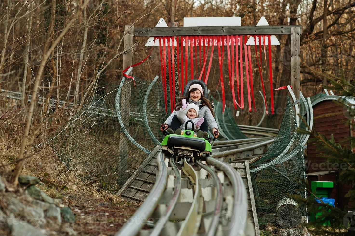 Mother with daughter ride electric sleigh on rails. photo