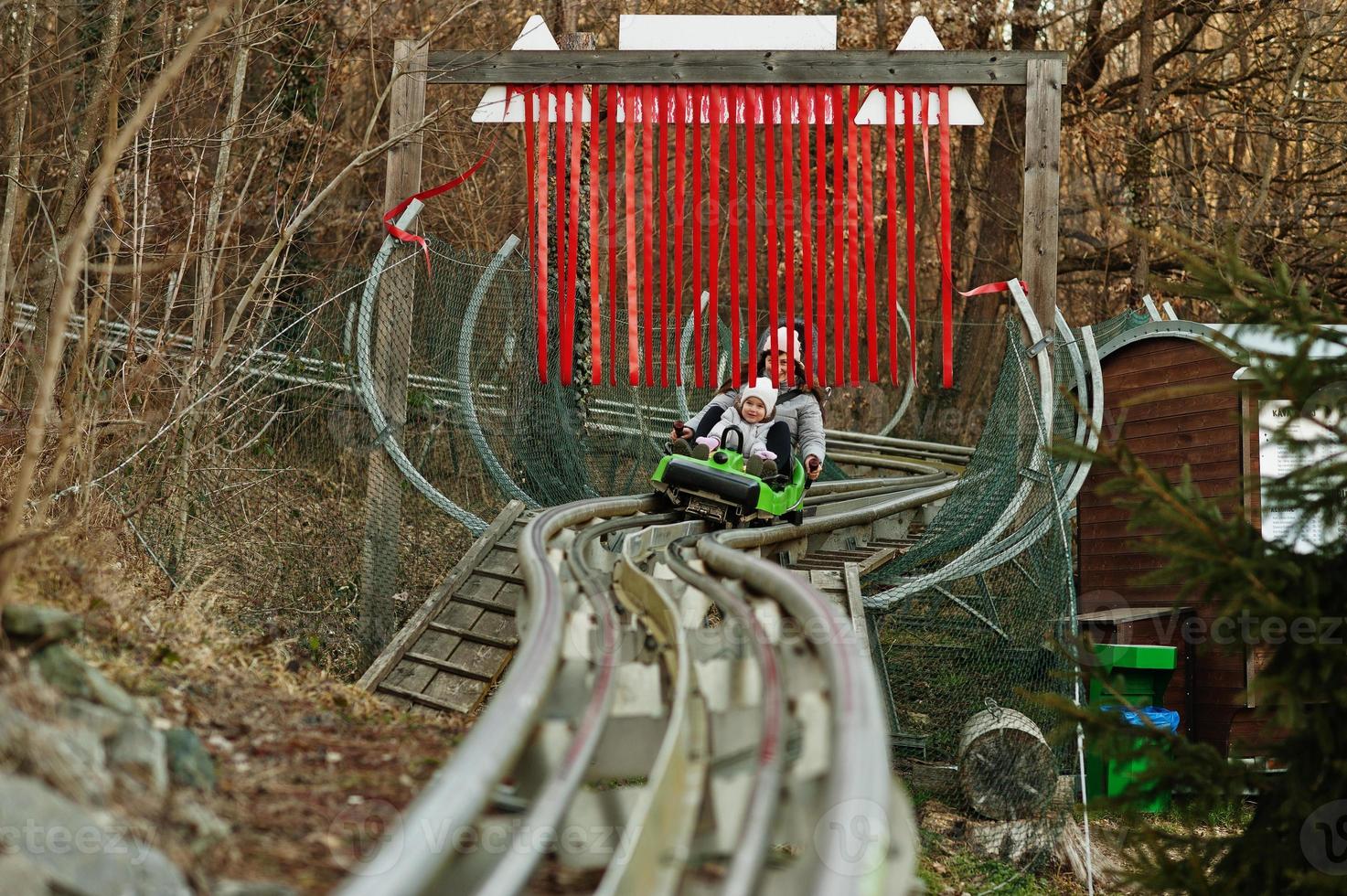 Mother with daughter ride electric sleigh on rails. photo