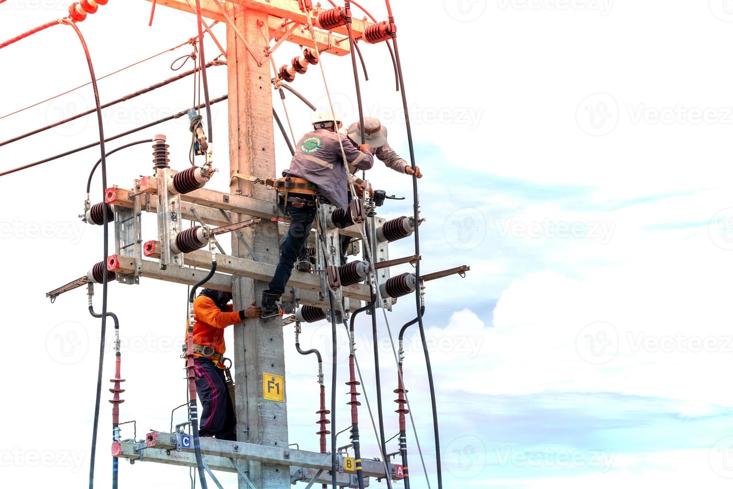 Electricians are climbing on electric poles to install and repair power lines, Some technicians do not wear helmets. may be dangerous photo