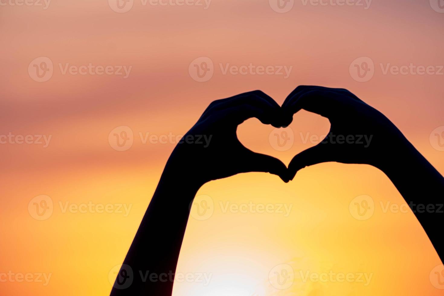 mujer de silueta pintada a mano en forma de corazón con puesta de sol, fondo de ambiente naranja, concepto de amor feliz día de san valentín foto