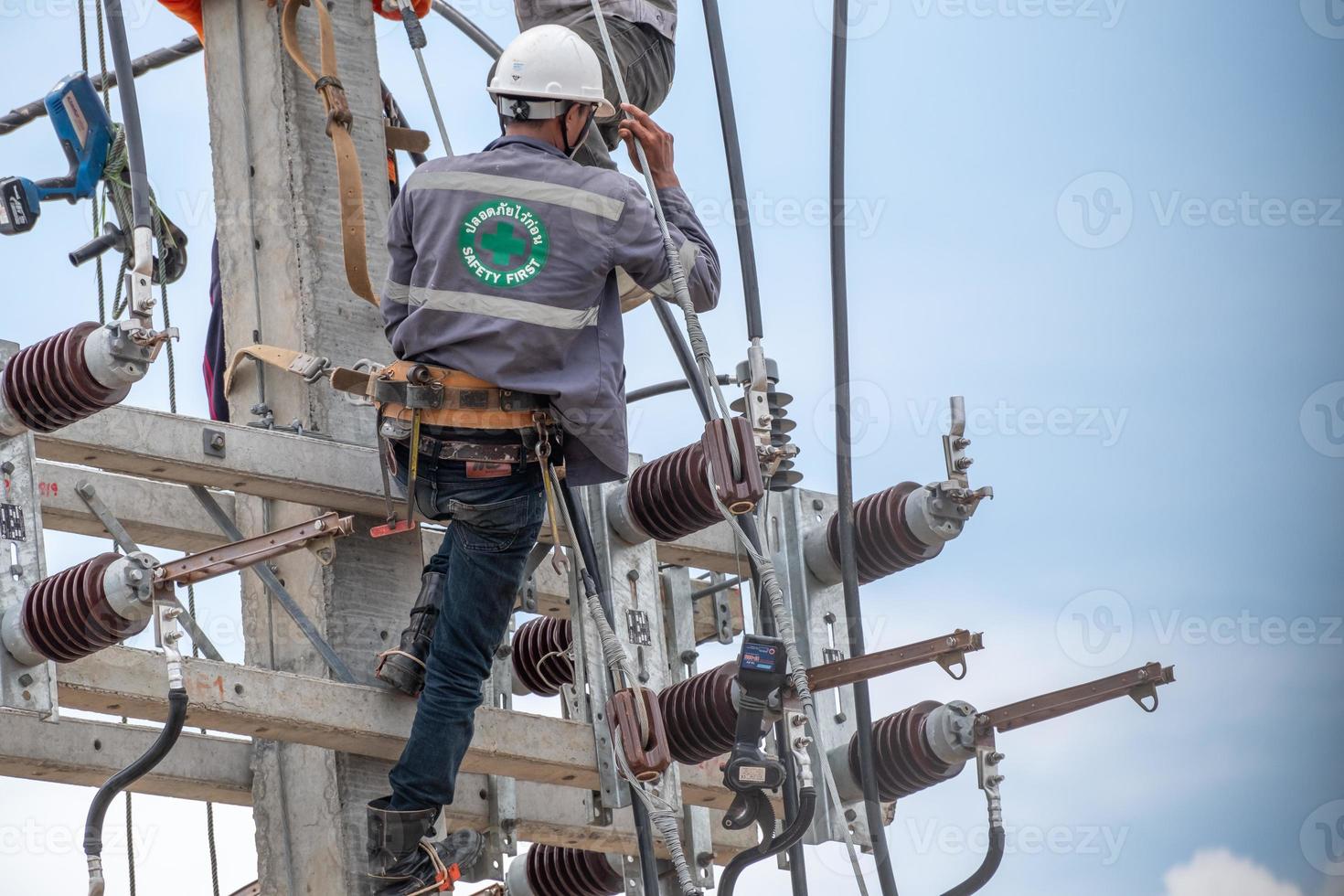 Electricians are climbing on electric poles to install and repair power lines, Some technicians do not wear helmets. may be dangerous photo