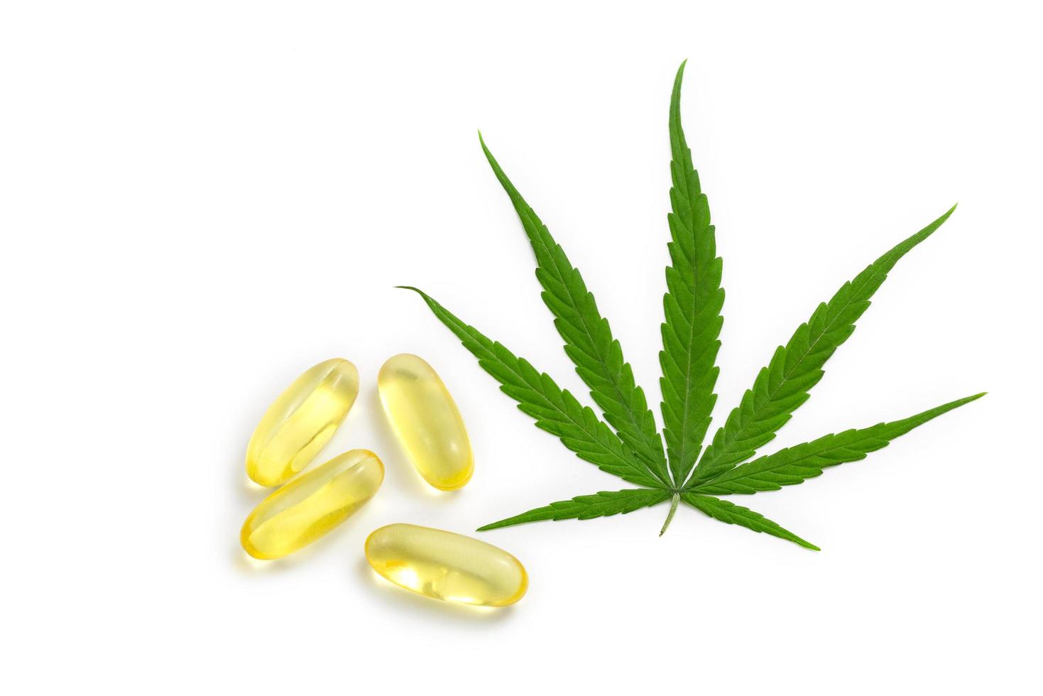 Hemp oil capsules and cannabis leaves on a white background, CBD hemp oil, medical marijuana concept. photo
