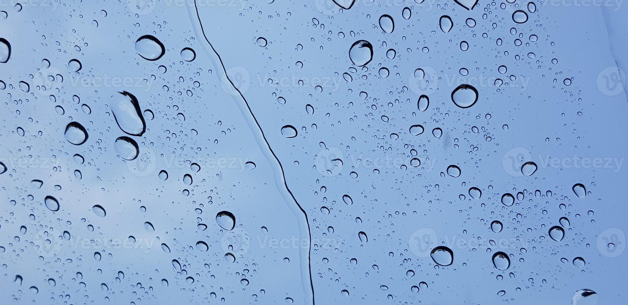 Water droplets perspective through window glass surface against blue sky good for multimedia content photo