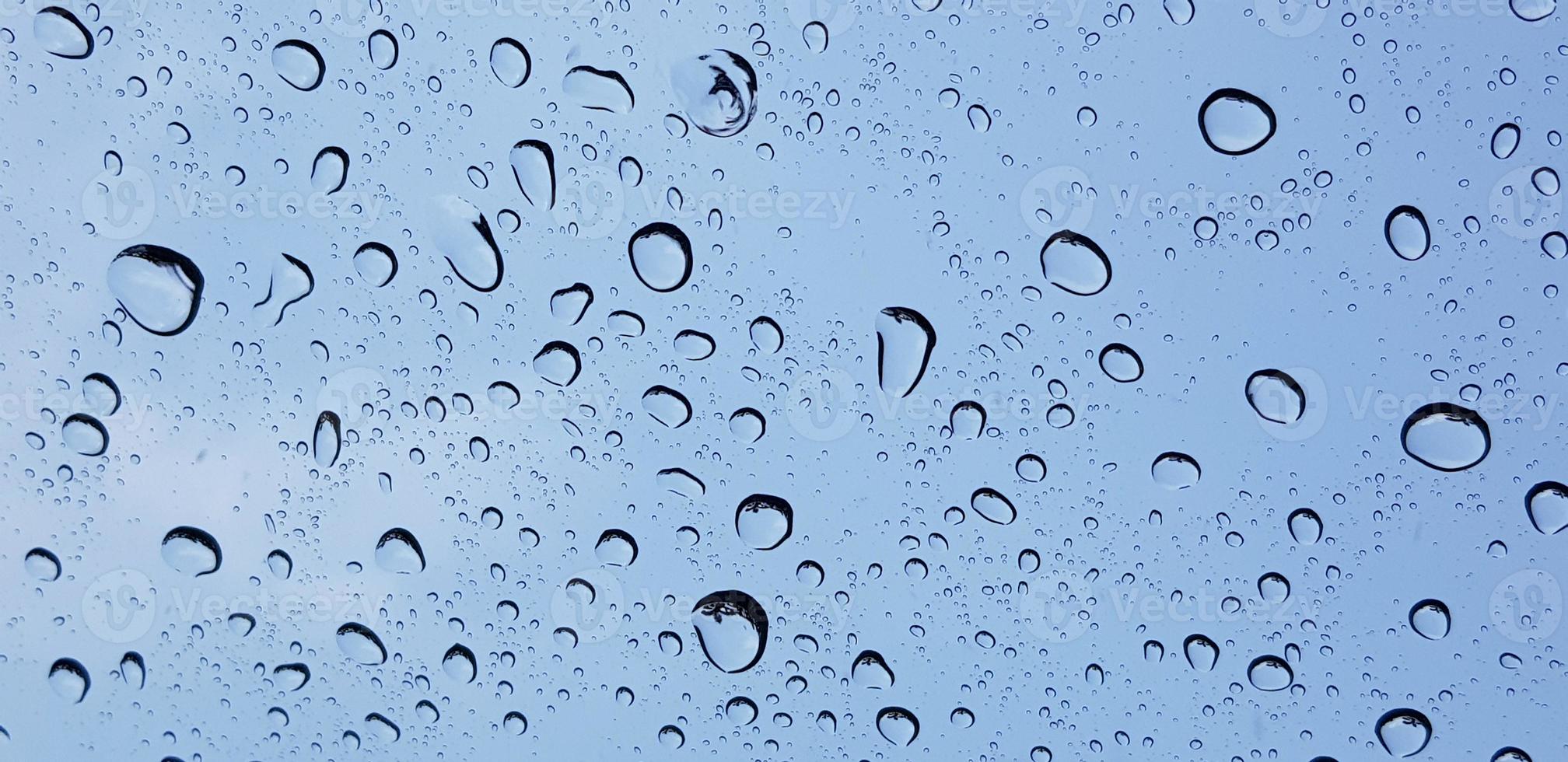 Perspectiva de gotas de agua a través de la superficie de cristal de la ventana contra el cielo azul bueno para contenido multimedia foto