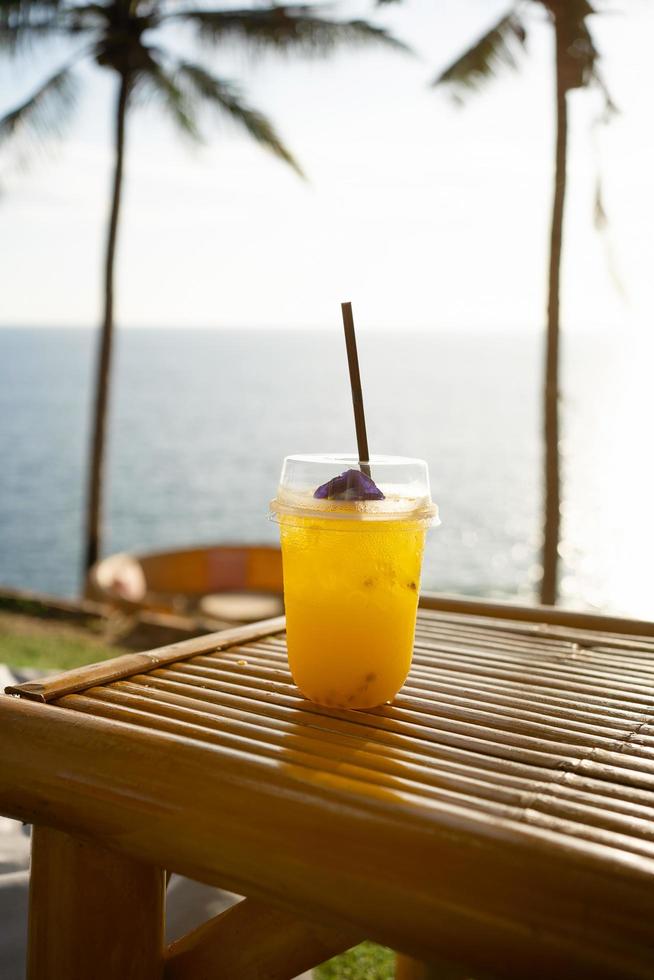 Fresh Orange juice glass on top table seaside cafe holiday coconut trees background. Water drink summer photo