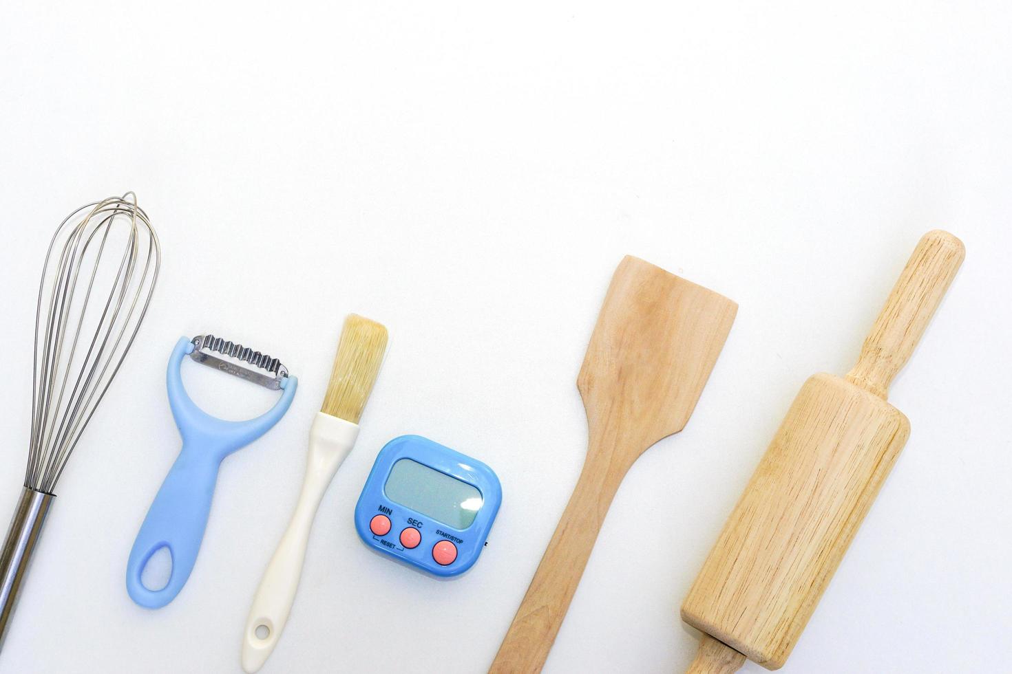 Top view kitchenware wooden rolling pin, wooden spatula and egg beater on white background. photo