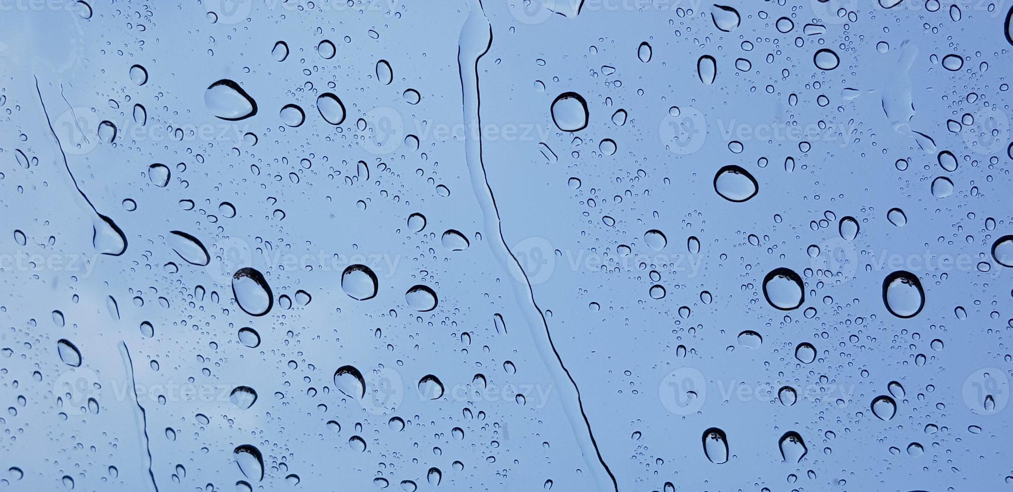 Perspectiva de gotas de agua a través de la superficie de cristal de la ventana contra el cielo azul bueno para contenido multimedia foto