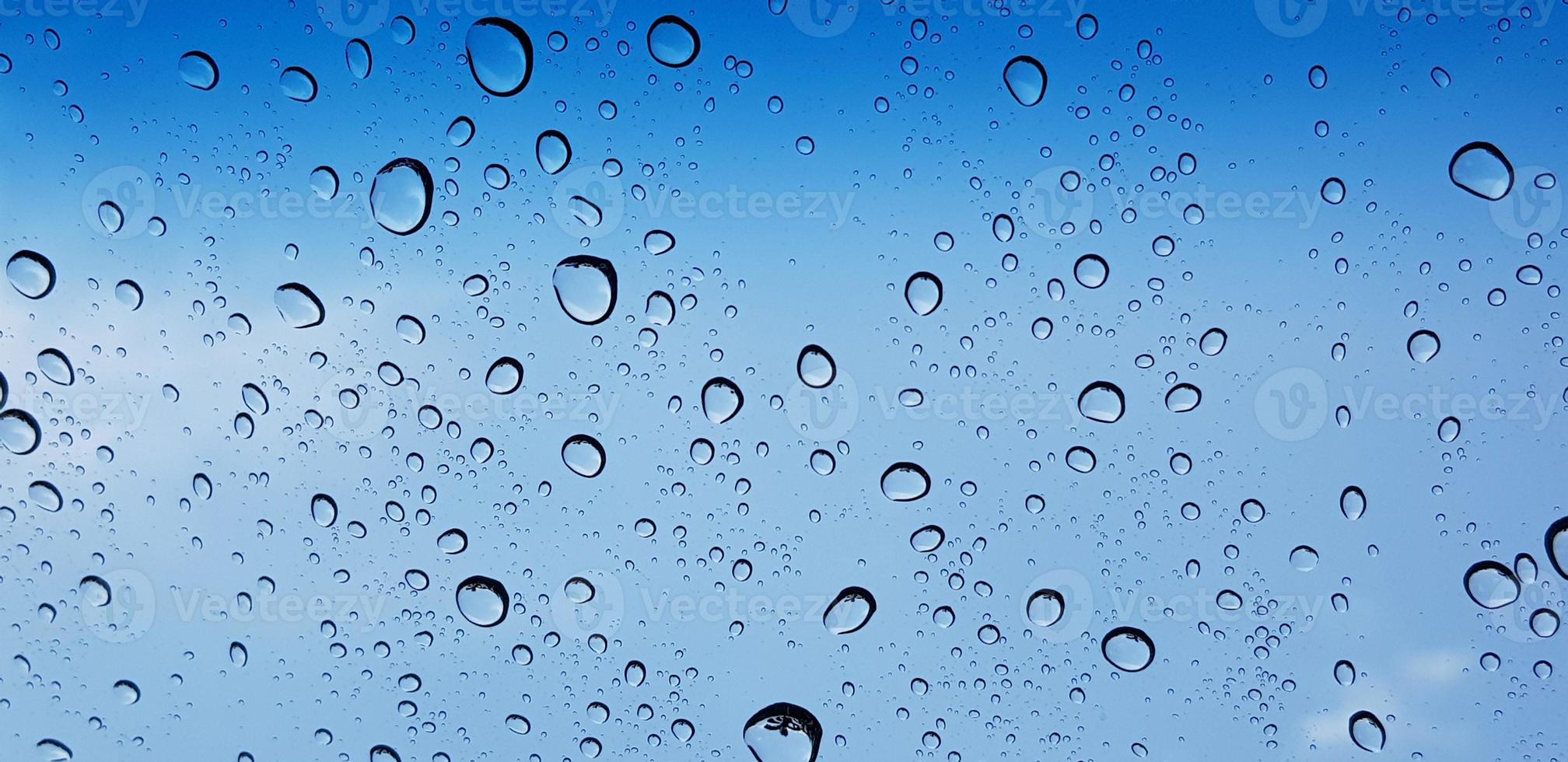 Water droplets perspective through window glass surface against blue sky good for multimedia content photo