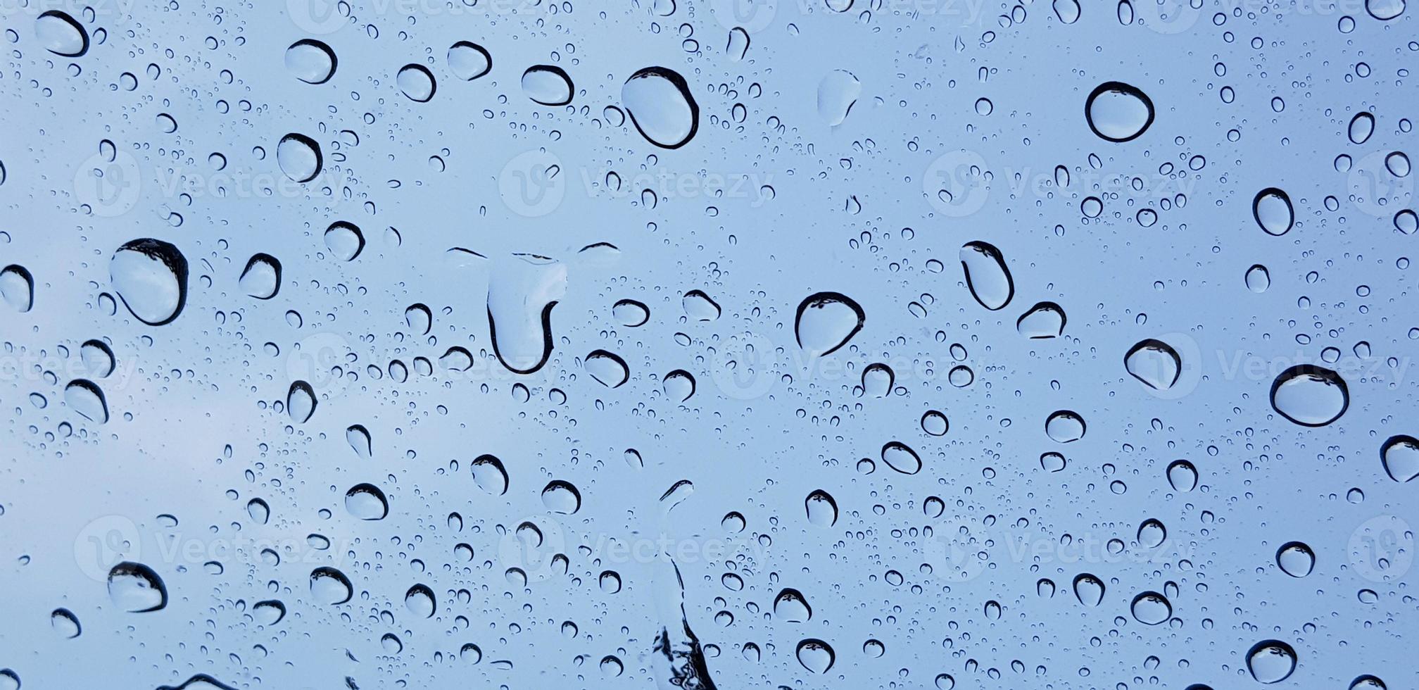 Perspectiva de gotas de agua a través de la superficie de cristal de la ventana contra el cielo azul bueno para contenido multimedia foto