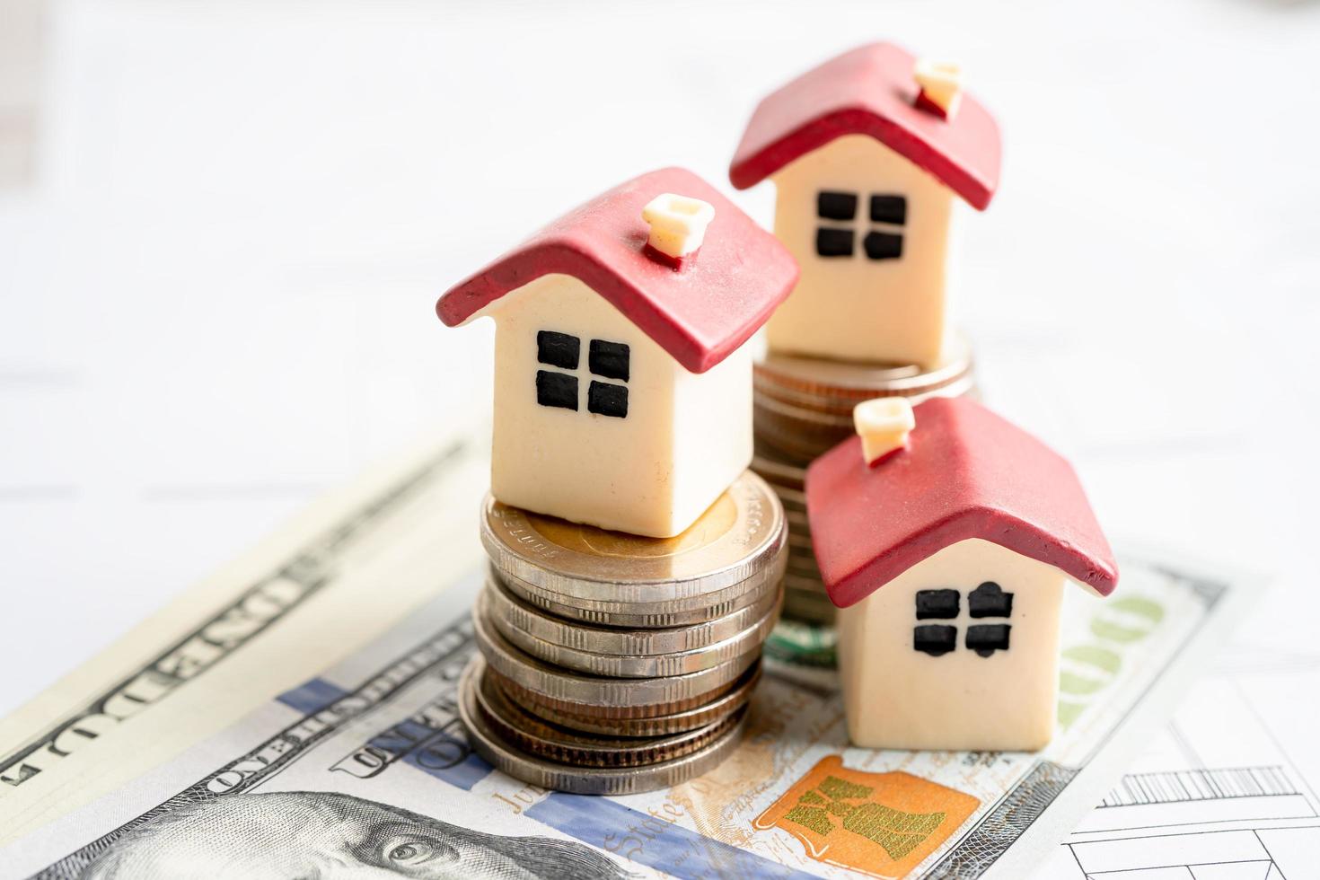 casa con monedas apiladas y dinero en dólares estadounidenses en la casa del plan, concepto de financiación de préstamos hipotecarios. foto