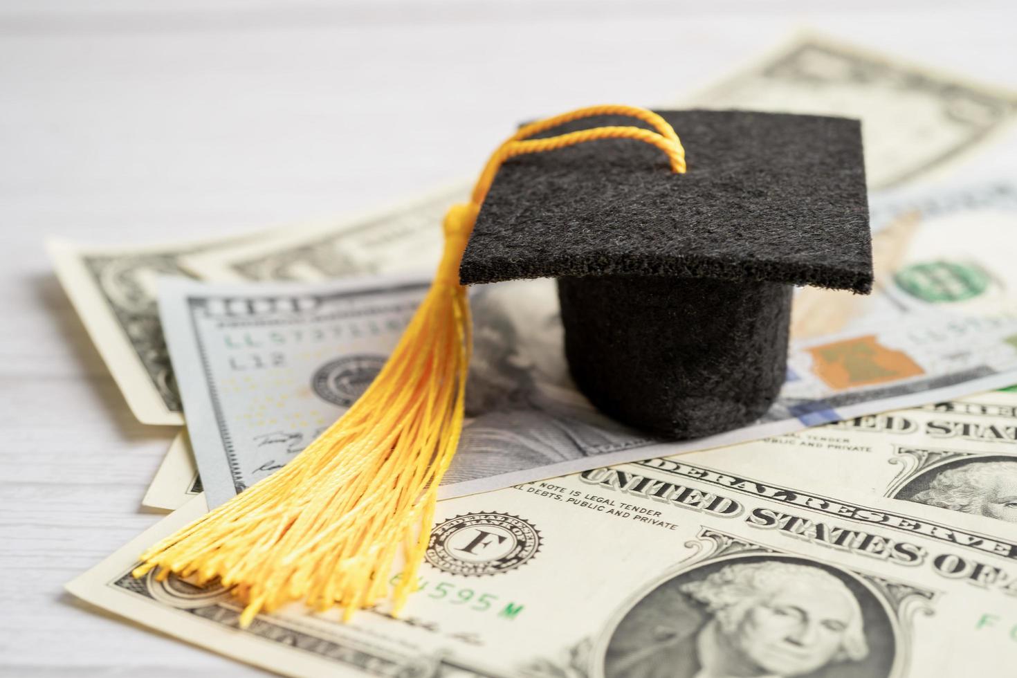 sombrero de la brecha de graduación en el dinero de los billetes en dólares estadounidenses, concepto de enseñanza de aprendizaje de la tarifa de estudio de educación. foto