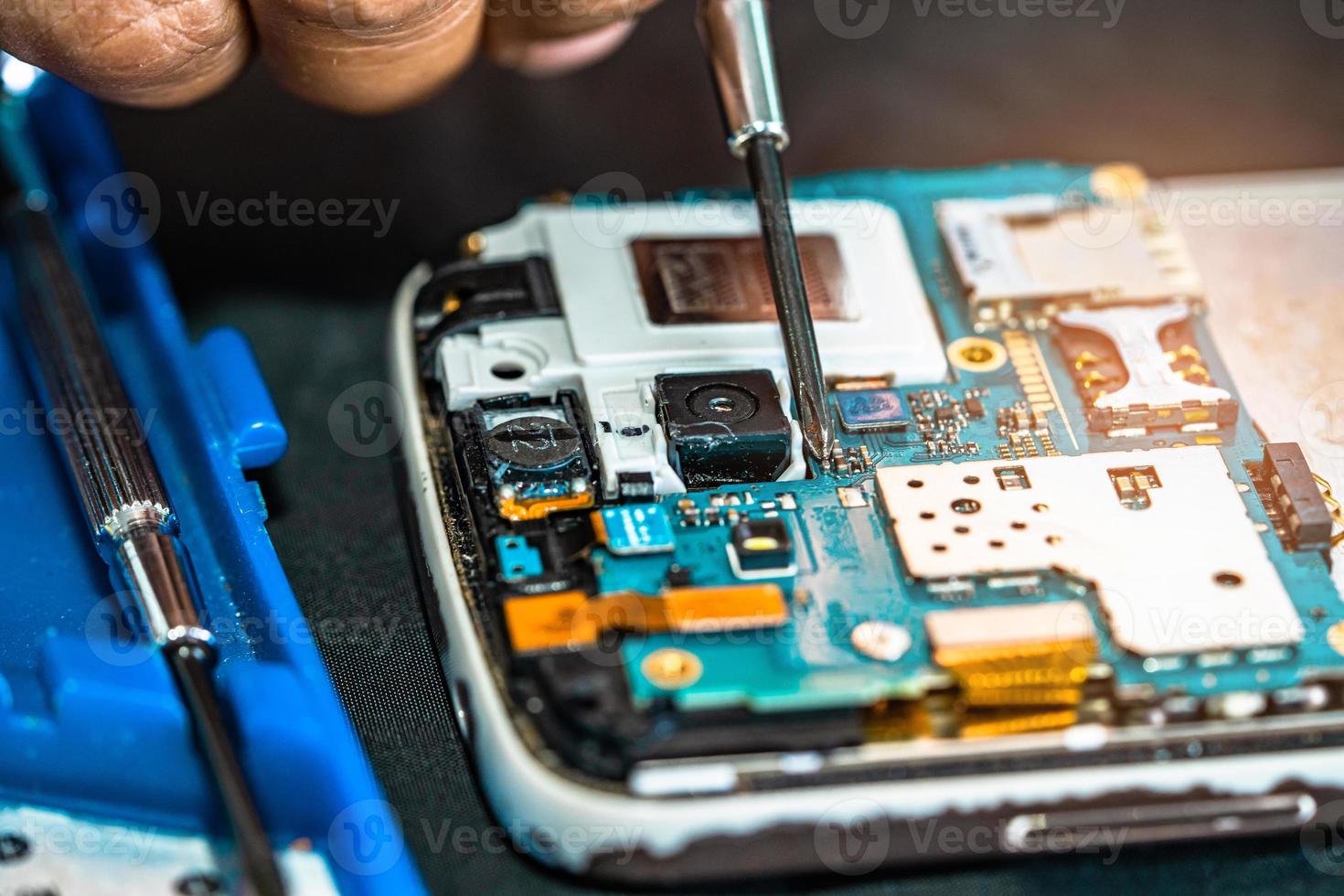 técnico que repara el interior del teléfono móvil con un soldador. circuito integrado. el concepto de datos, hardware, tecnología. foto