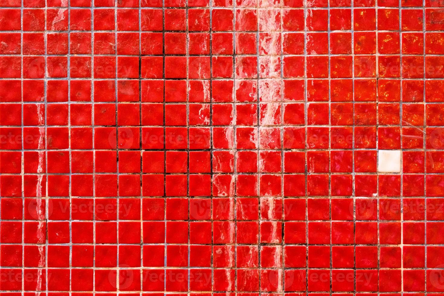 Small red dirty ceramic tiles on the building facade, retro mosaic wall surface, grunge texture and pattern, background. photo