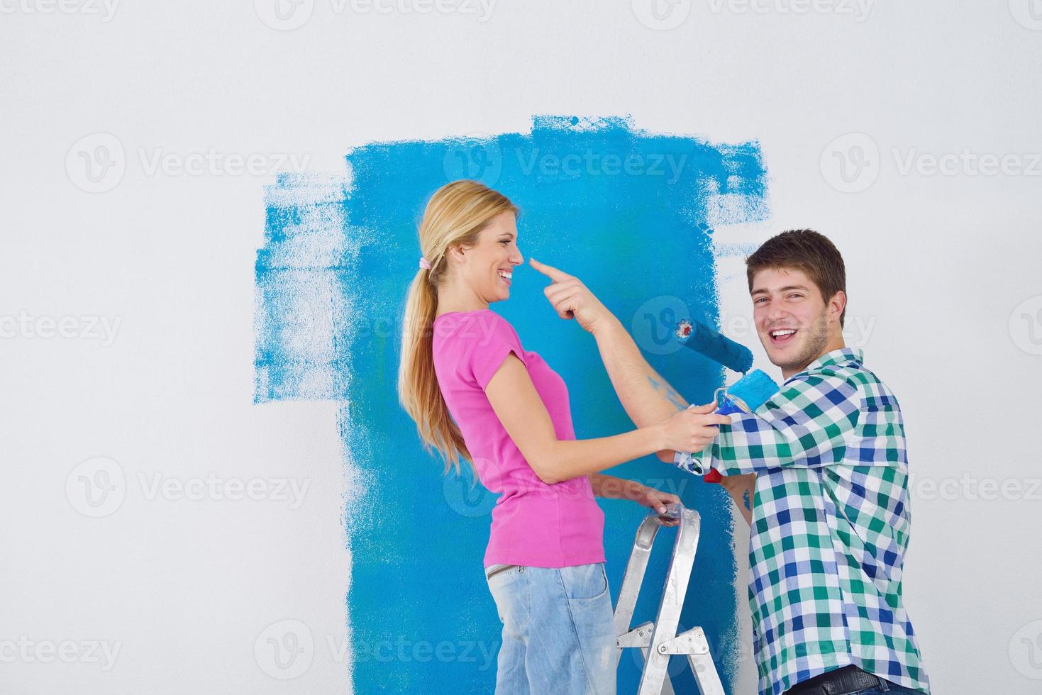 happy couple paint wall at new home photo