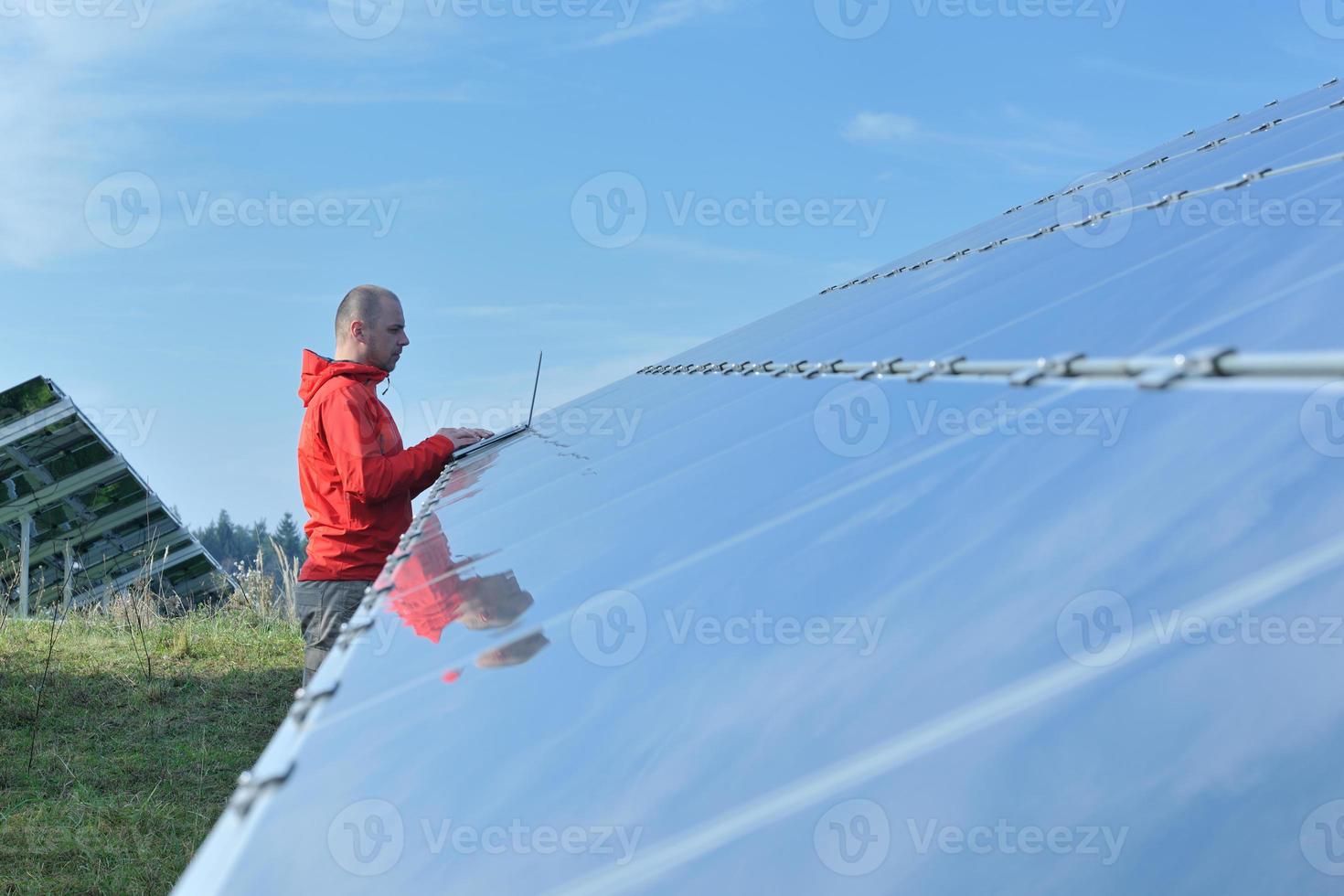 engineer using laptop at solar panels plant field photo