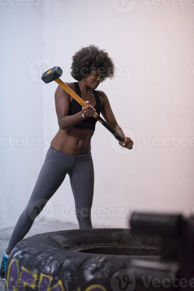 black woman workout with hammer and tractor tire photo