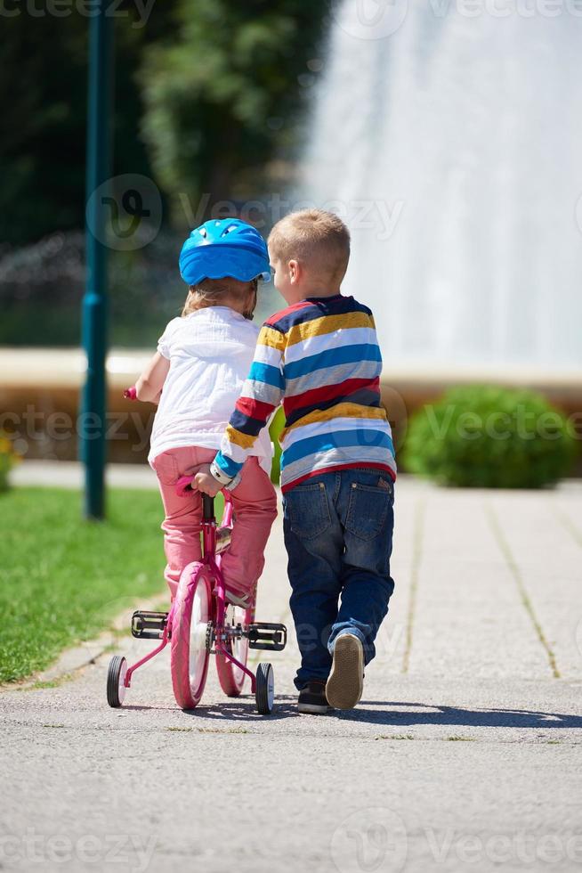 Boy and girl in park learning to ride a bike photo