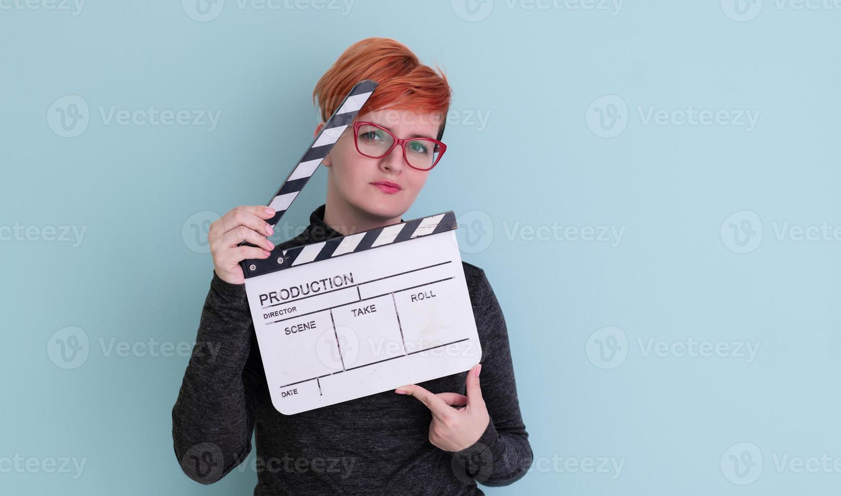 redhead woman holding movie  clapper on cyan background photo