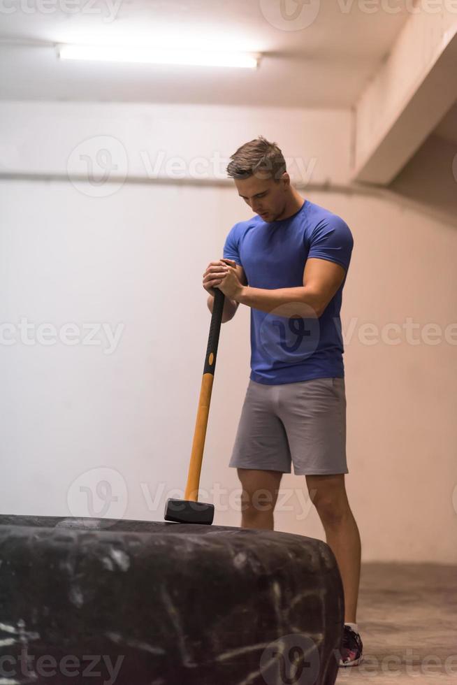 entrenamiento de hombre con martillo y neumático de tractor foto