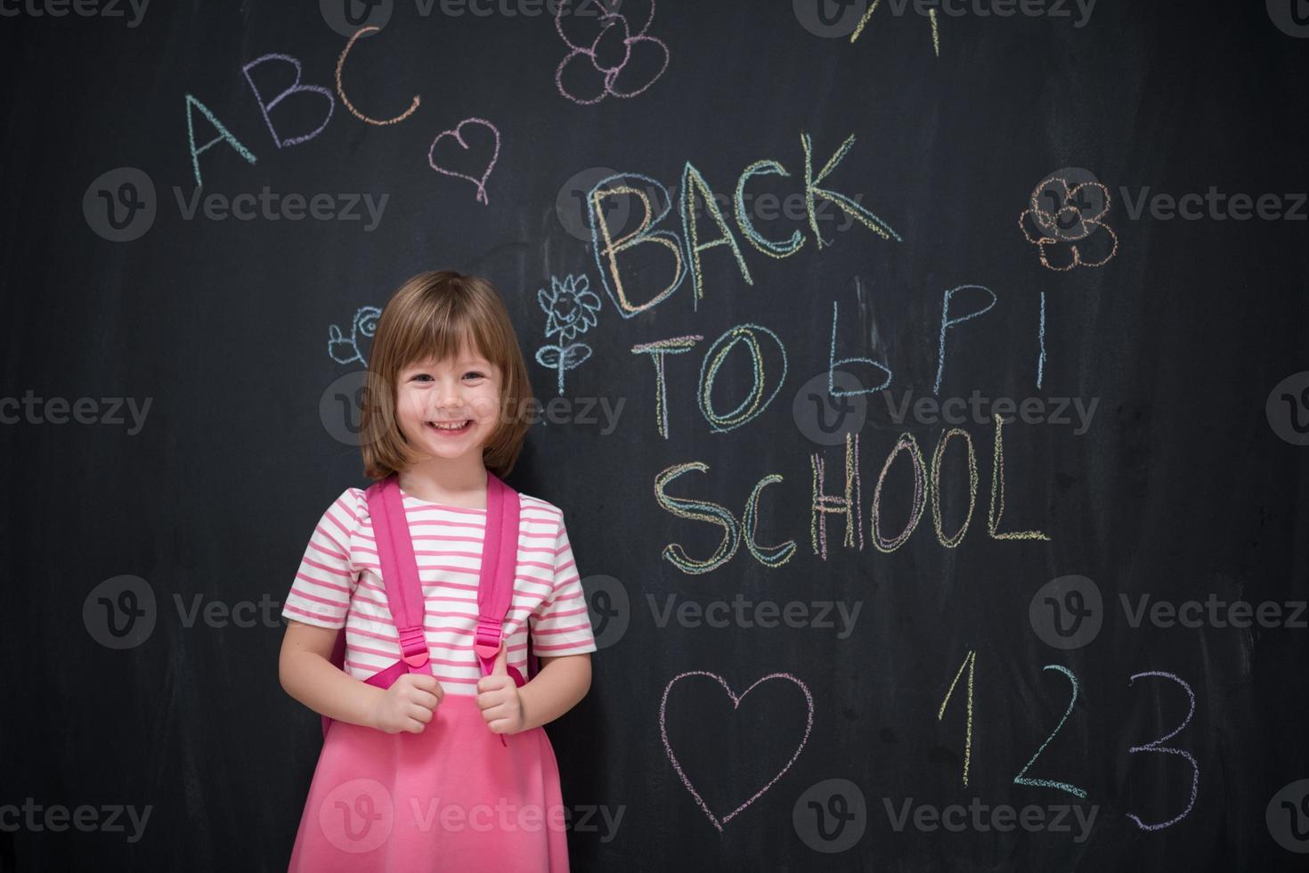 school girl child with backpack writing  chalkboard photo