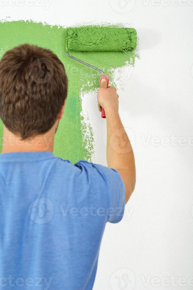 handsome young man paint white wall in color photo