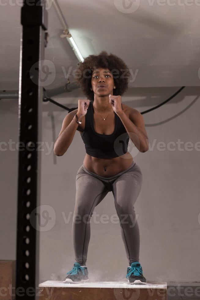 atleta femenina negra está realizando saltos de caja en el gimnasio foto