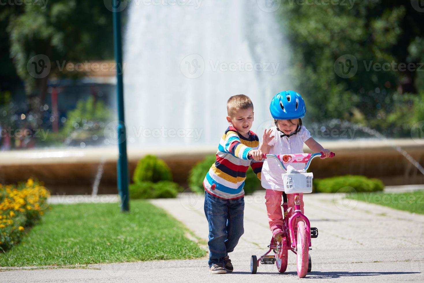 Boy and girl in park learning to ride a bike photo