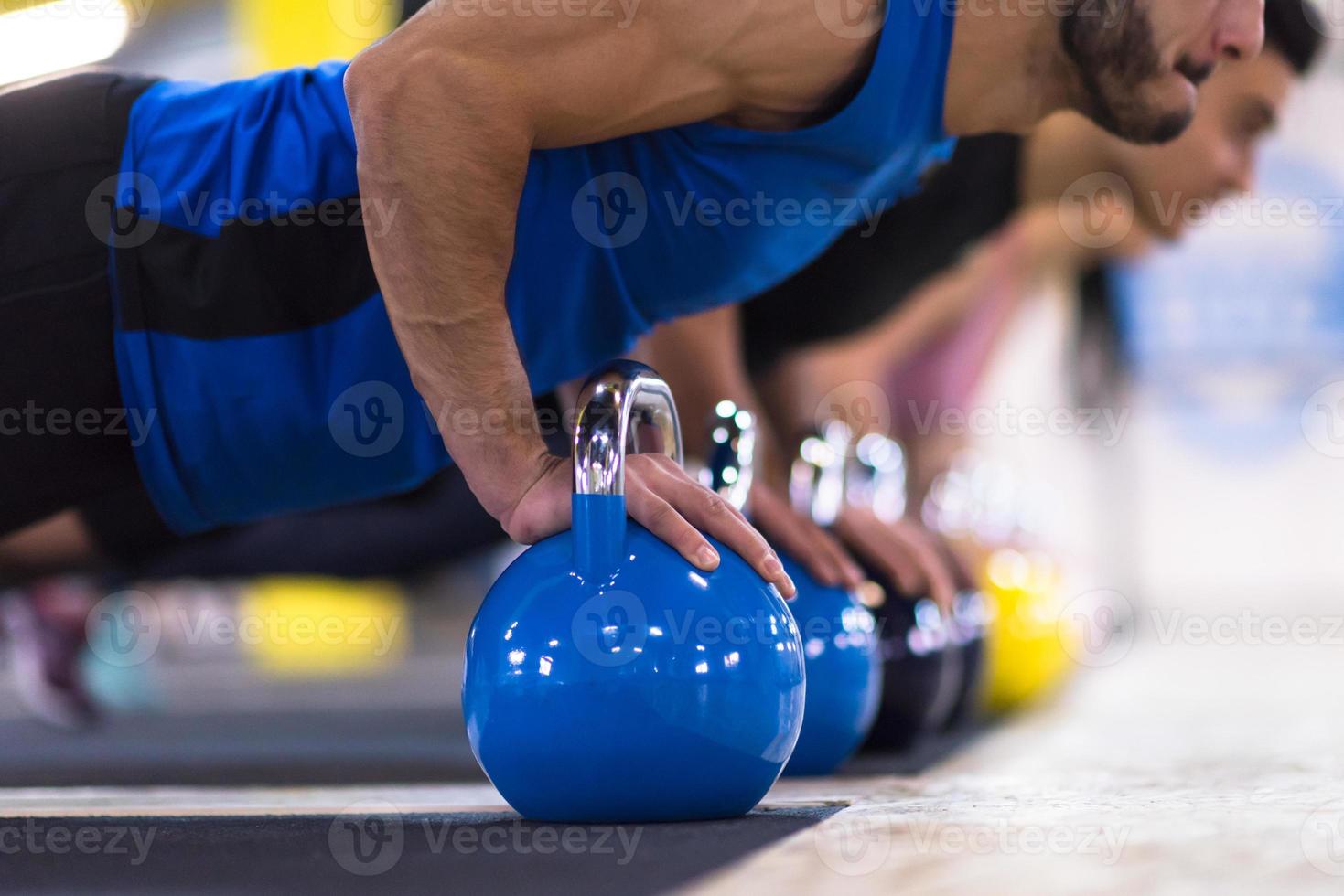 young athletes doing pushups with kettlebells photo