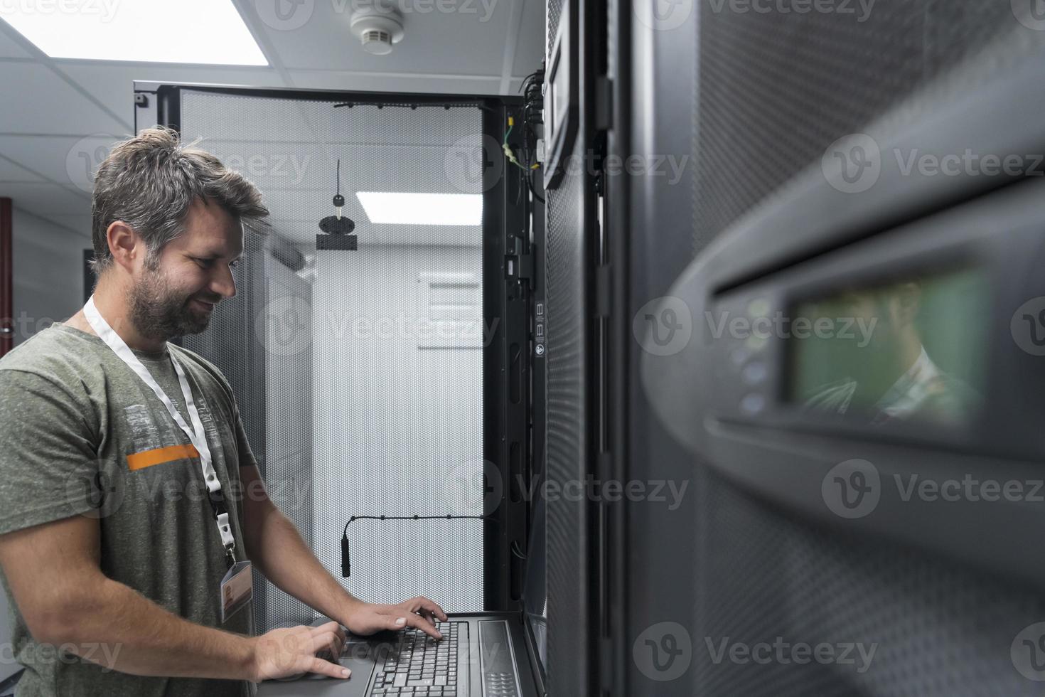 Data Center Engineer Usaing Keyboard on a Supercomputer Server Room Specialist Facility with Male System Administrator photo