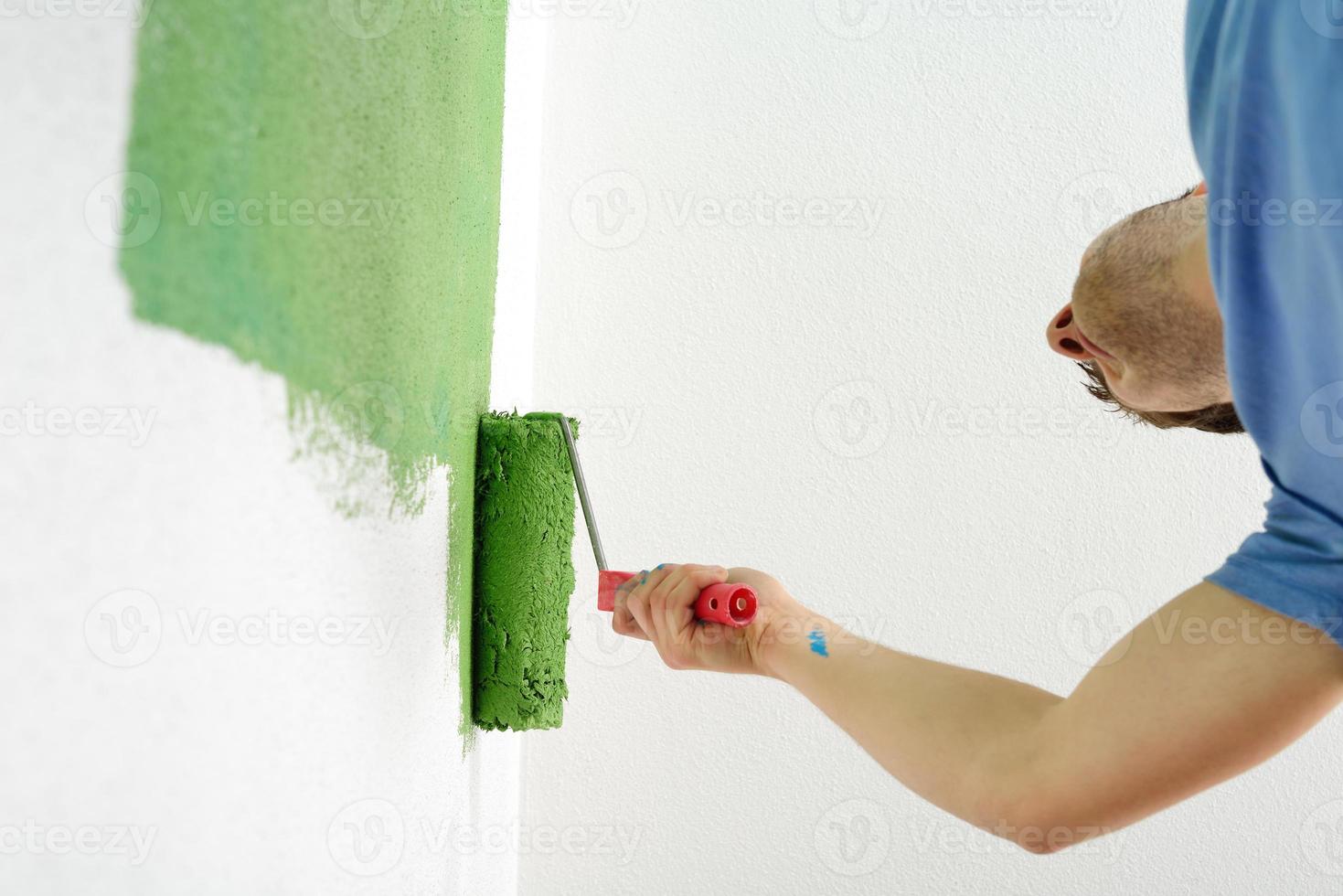 handsome young man paint white wall in color photo