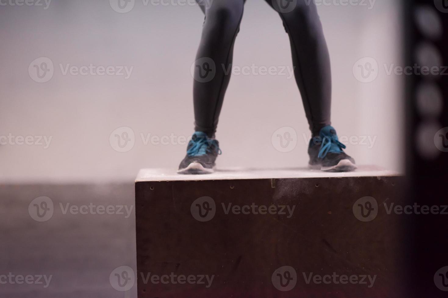 black woman is performing box jumps at gym photo