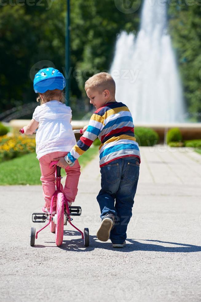 Boy and girl in park learning to ride a bike photo