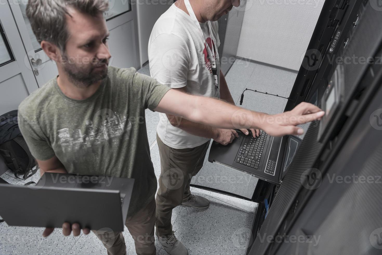 Technicians team updating hardware inspecting system performance in super computer server room or cryptocurrency mining farm. photo