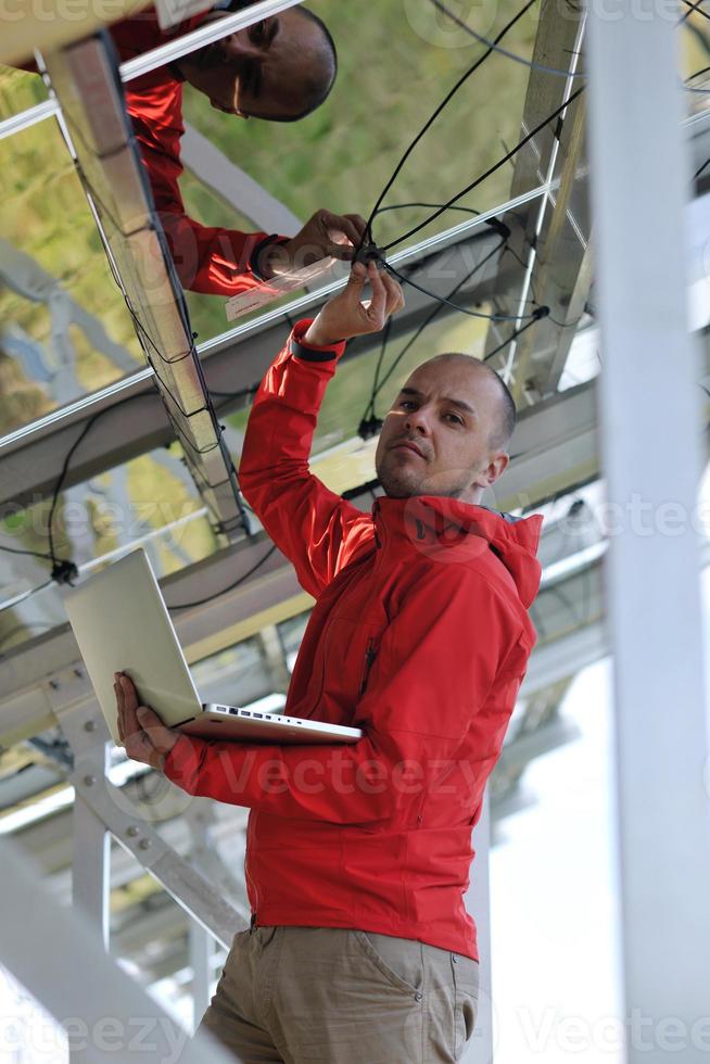 engineer using laptop at solar panels plant field photo