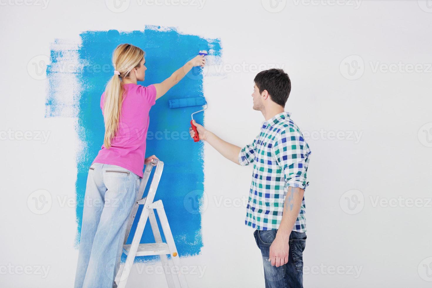 happy couple paint wall at new home photo