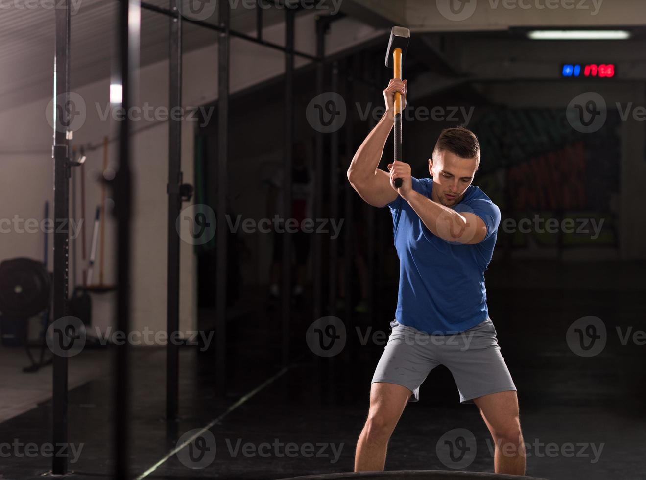 man workout with hammer and tractor tire photo