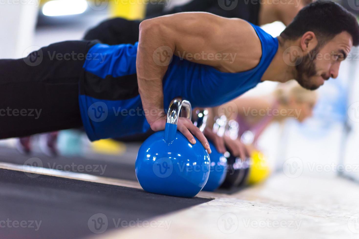 young athletes doing pushups with kettlebells photo