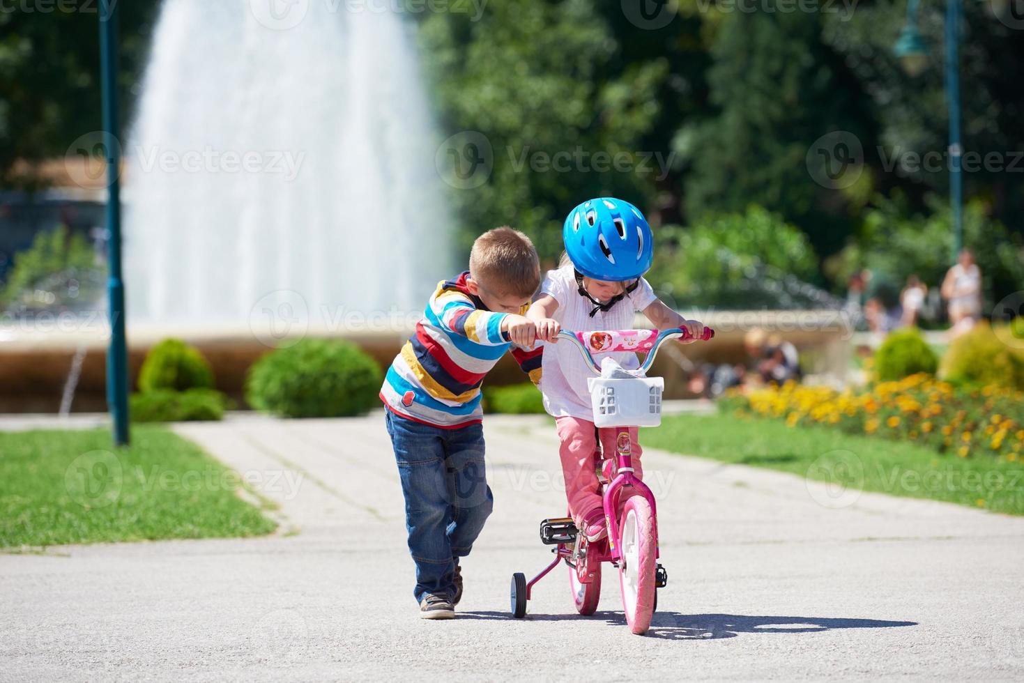 Boy and girl in park learning to ride a bike photo